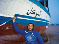 Patrick Zachmann // M. Ali Ghommidh, 19 ans, pose devant le bateau sur lequel il a embarqué, avec cent autres migrants clandestins, en direction de l’Europe. Le chalutier a failli sombrer, et ses passagers ont été sauvés par la marine tunisienne, Zarzis, avril 2011
Magnum Photos